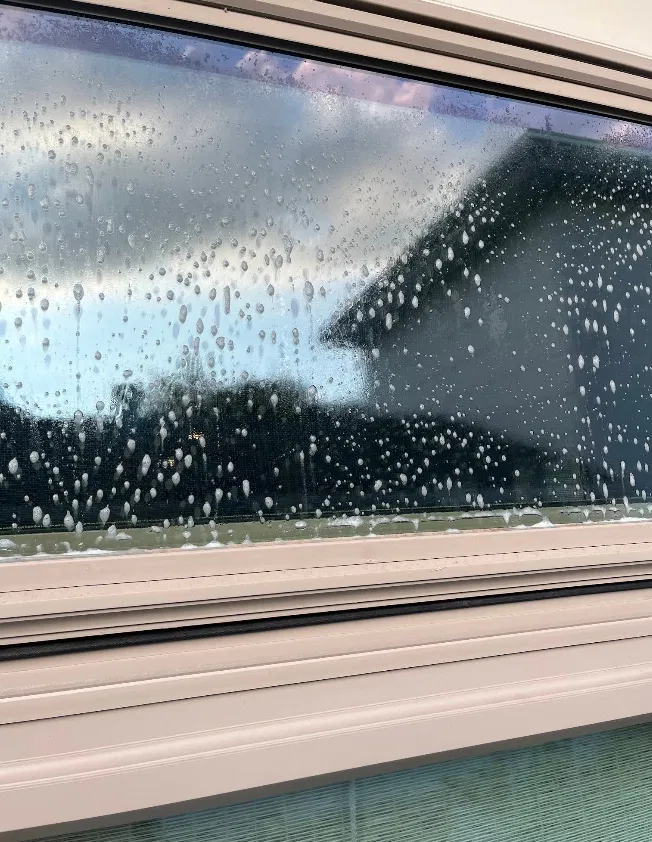 Window covered in soap suds being cleaned